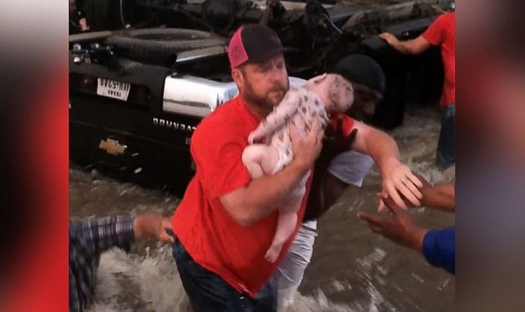 Homem retira o bebê desacordado do carro que estava preso na correnteza (Foto: Reprodução/Facebook)